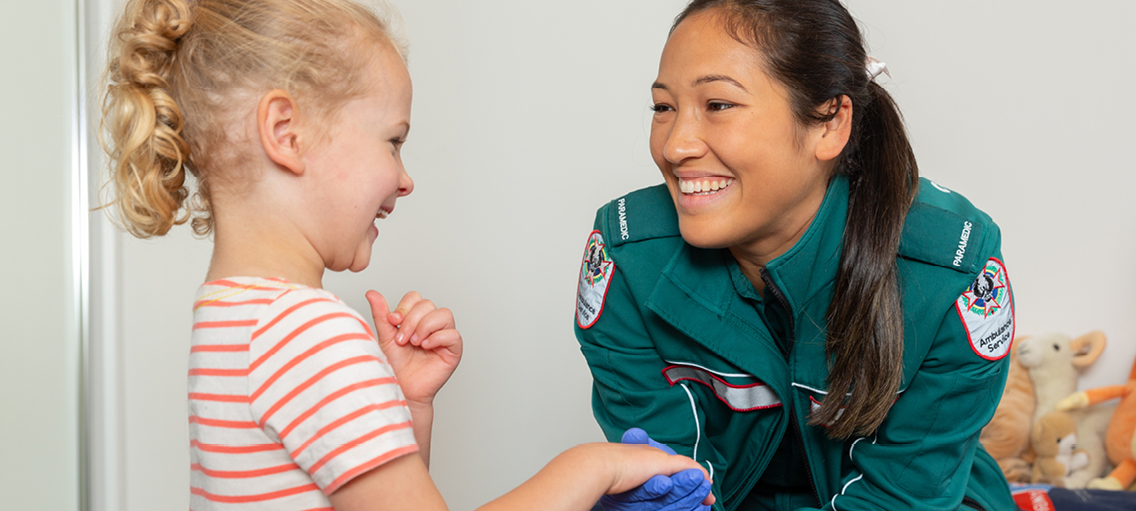 Paramedic smiling holding a young girls hand